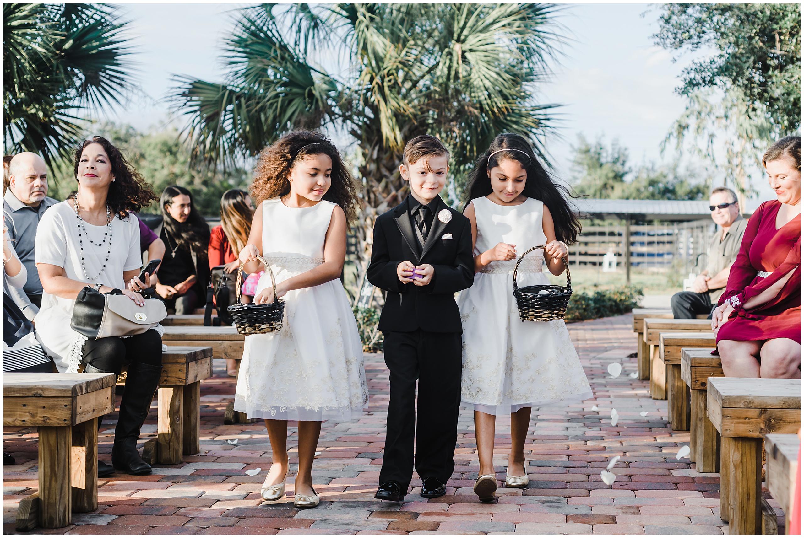 Bride and Groom's son escorting flower girls down the aisle during their wedding