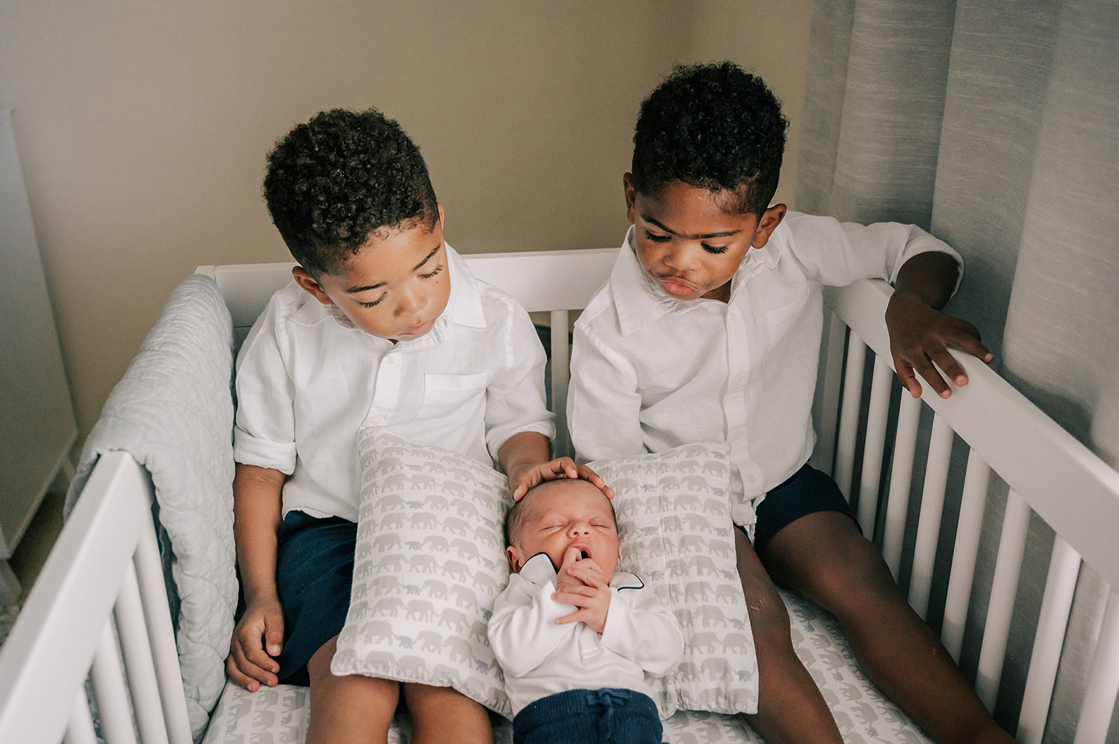 Twin boys sit in a crib with their sleeping newborn baby cousin Science Safari