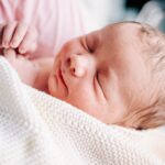 Details of a sleeping newborn baby with a white knit blanket