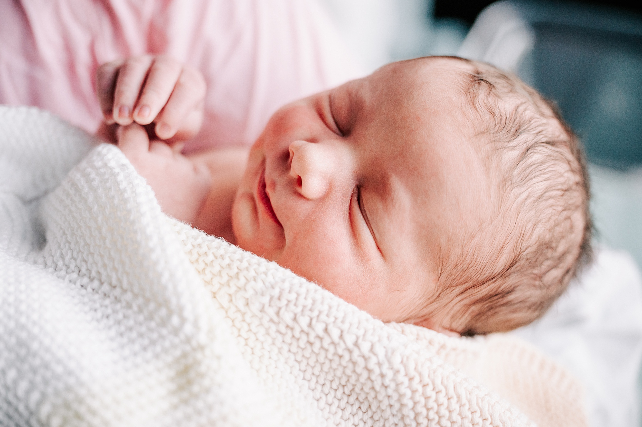 Details of a sleeping newborn baby with a white knit blanket