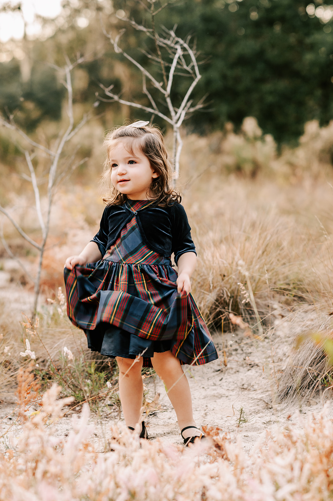 A toddler girl stands in a forest trail playing with her dress Greensboro Fall Activities