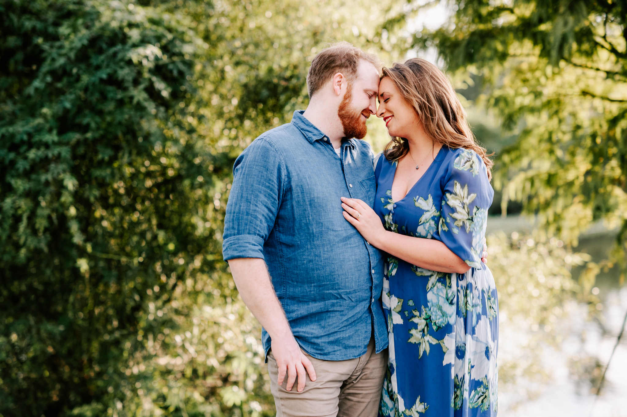 Happy mom and dad snuggle while exploring a park at sunset