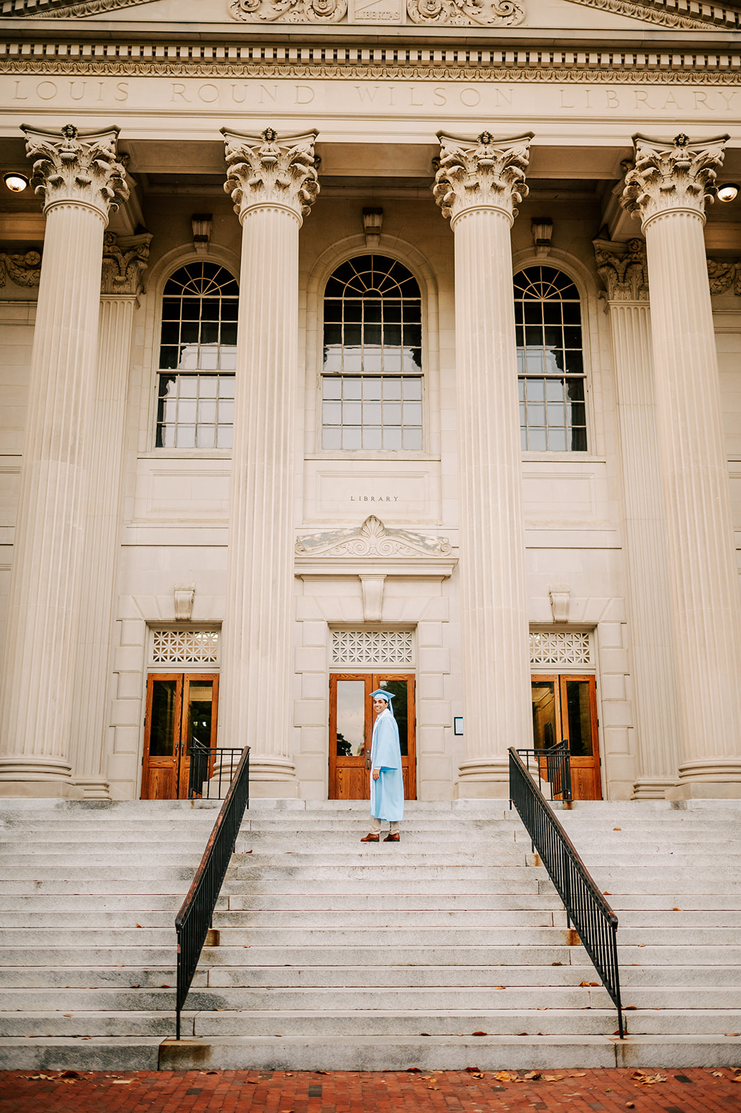 One of the UNC-Chapel Hill Graduates walks up the steps of the Library in cap and gown