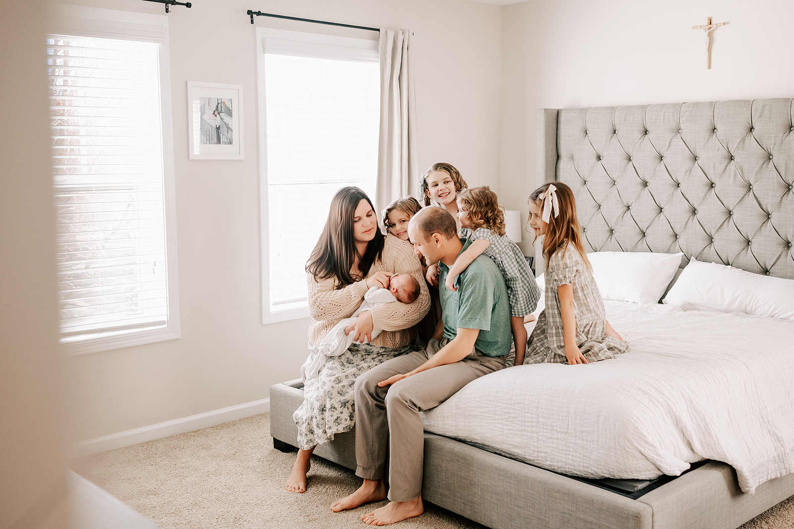 A mom holds a newborn as her four toddler daughters climb on dad and bed next to her before one of the birthday parties in Winston-Salem